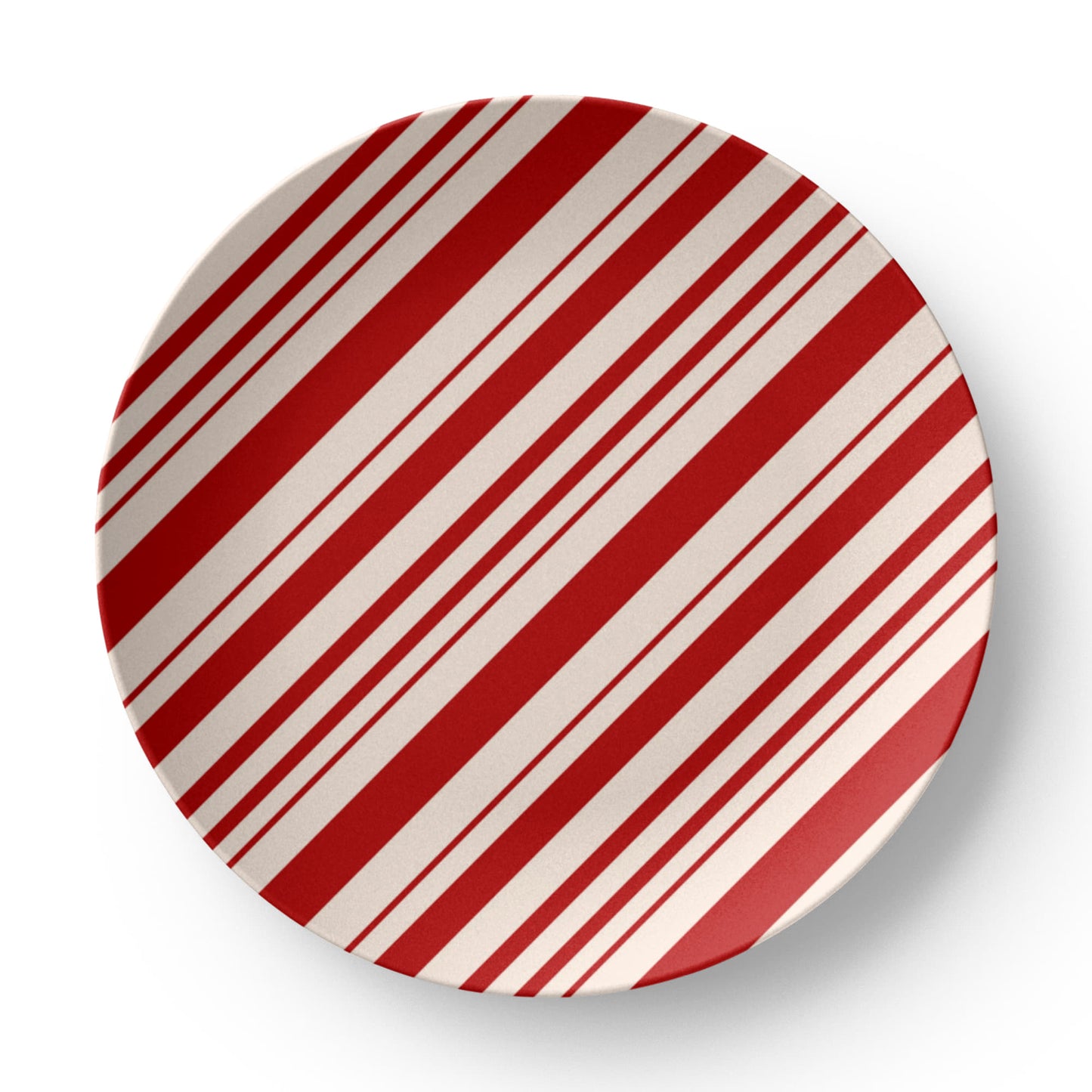 Red and white striped holiday plate set on a wooden table with a full festive Christmas dinner setting.