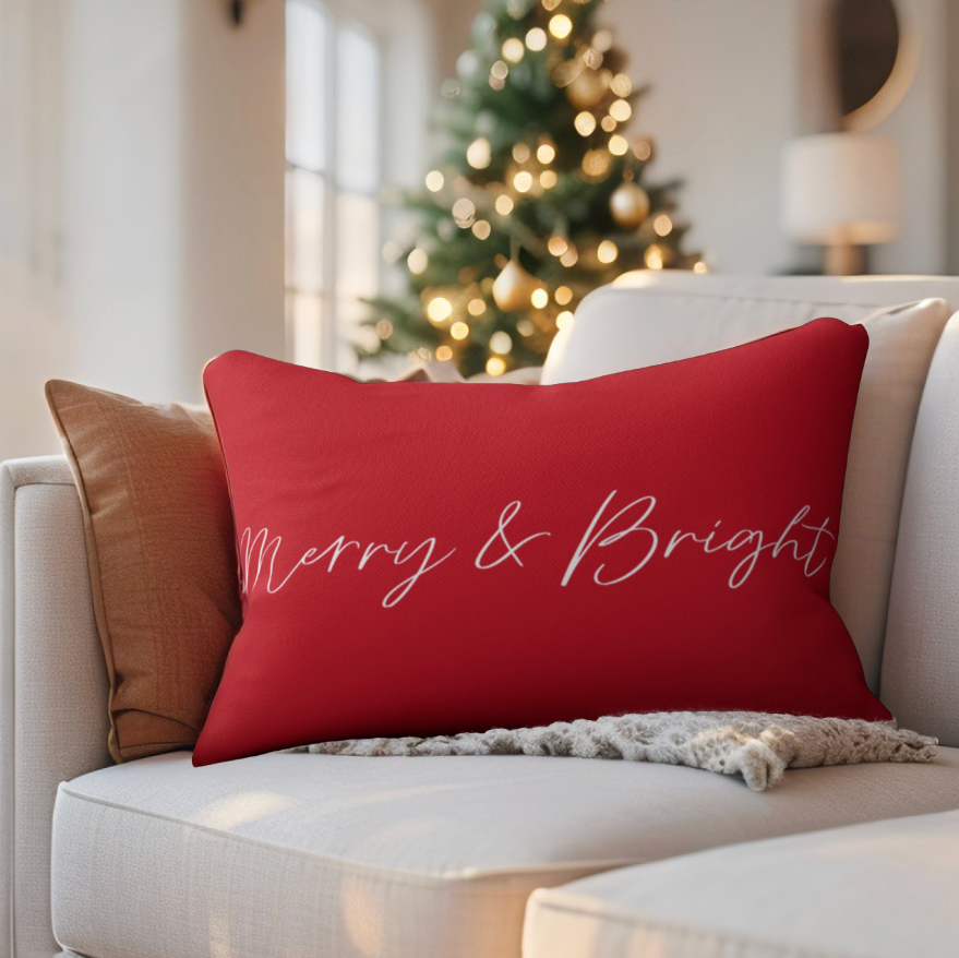 Red pillow with 'Merry & Bright' text on a white couch in a living room with a Christmas tree.