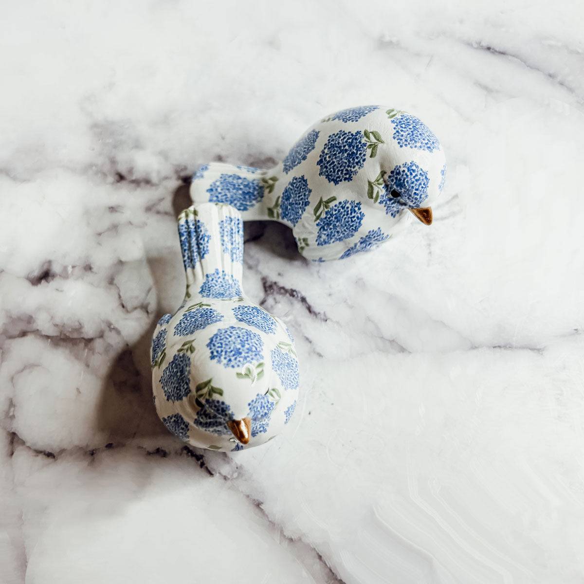 Grandmillennial blue and white bird figurine sitting on a dark wood coffee table.