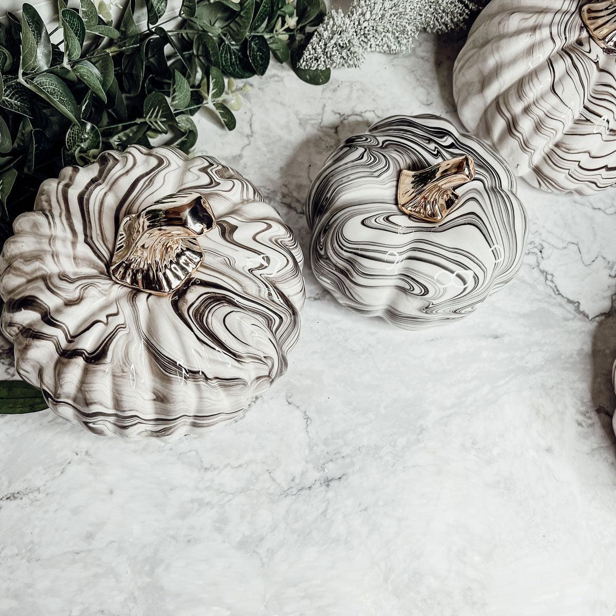 Close-up of high-end designer pumpkin decor showcasing the unique, handmade B&W marbled finish and gold metallic stem.