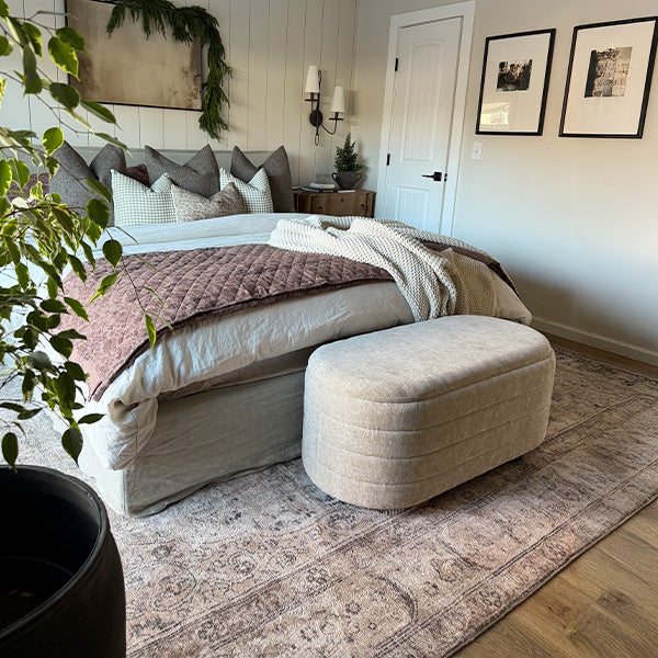 Upholstered storage bench set styled at the foot of a bedroom bed.