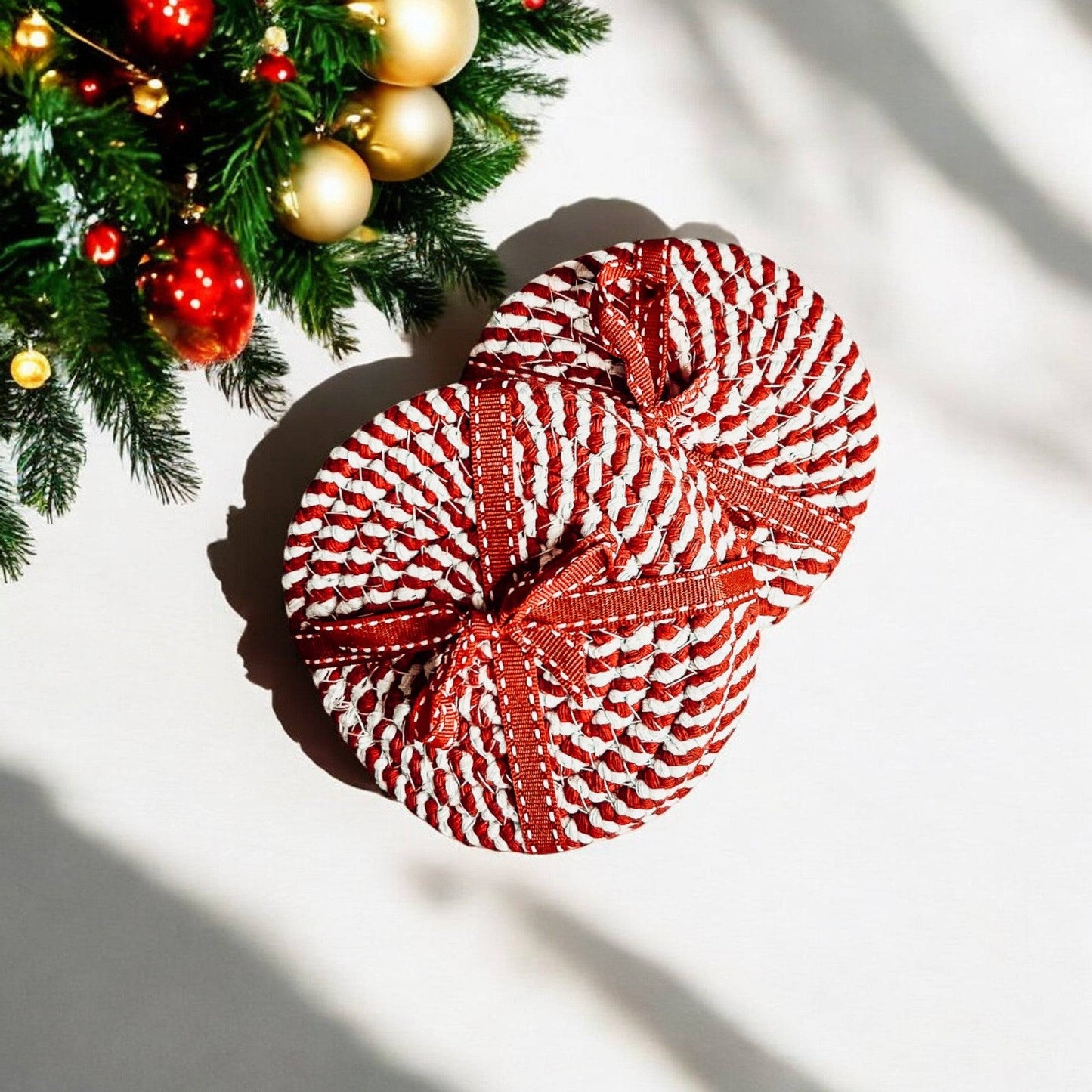 Close-up of red and white braided cotton rope coasters on a Christmas table setting, showing texture and size.