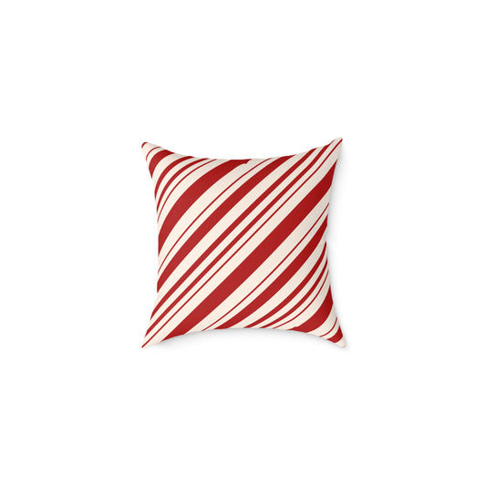 Red and white striped Christmas throw pillow styled on a cozy gray sofa with a holiday blanket.