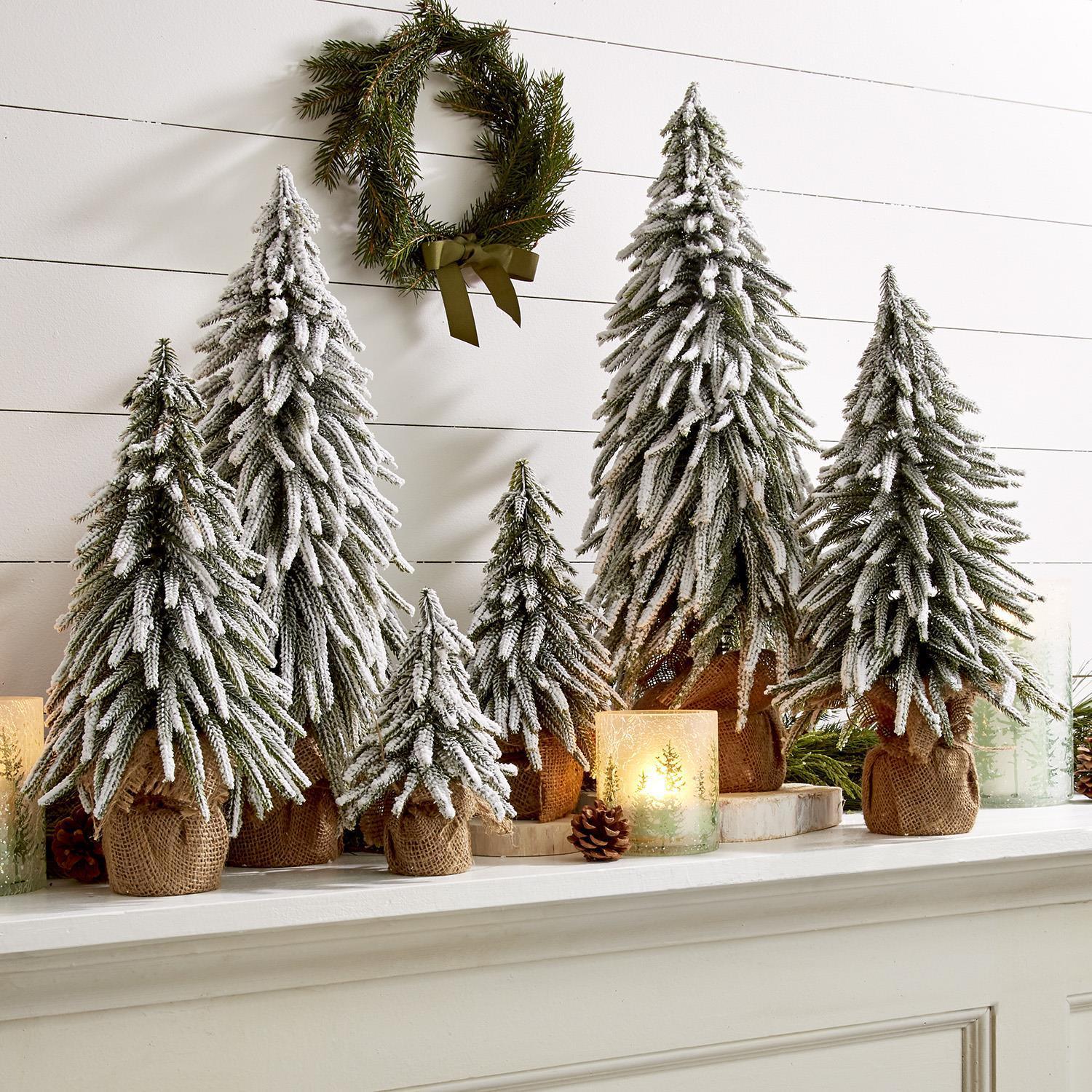 Set of 6 snow covered miniature flocked Christmas trees with jute bases for mantle display.