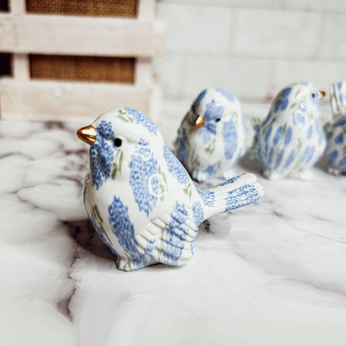 4-pack whimsical floral bird statues grouped as a blue and white mantel centerpiece.